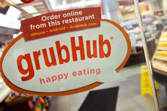 A sign for GrubHub is displayed on the door to a New York restaurant.
